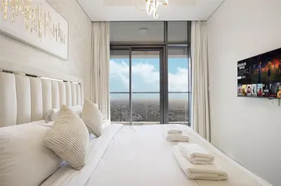 a bedroom with a white bed with a large window at Skyline Retreat, 2BDR Ensuite Comfort, City View in Dubai