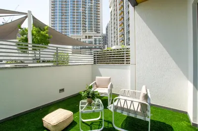 a balcony with two chairs and a table and grass at Modern Stay at The Crest Tower Near Meydan with Pool and Sauna in Dubai