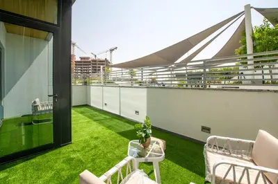 a balcony with green grass and chairs on a building at Modern Stay at The Crest Tower Near Meydan with Pool and Sauna in Dubai