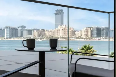 a table with two cups on a balcony with a view of the ocean at Beachfront Luxe 1BR Grand Bleu with Private Beach & Sea View in Dubai