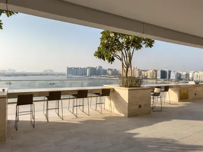 a table with chairs and a tree on a roof at Beachfront Luxe 1BR Grand Bleu with Private Beach & Sea View in Dubai