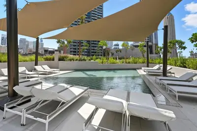 a pool with white lounge chairs and an umbrella at Deluxe Studio for 2 in Peninsula One, Business Bay in Dubai