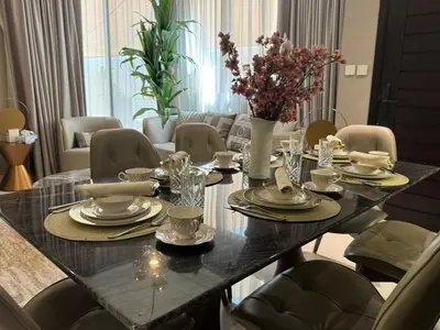 a dining room table with plates and glasses and flowers on it at Luxury Smart Home Villa Damac Hills 2 3BR Ensuite in Dubai