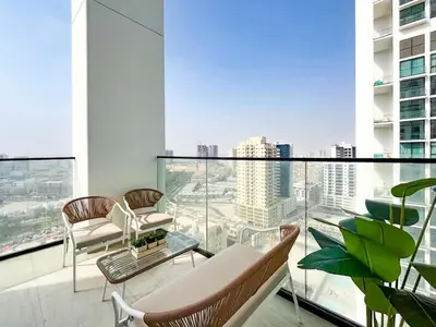 a balcony with chairs and tables on a building at Warm Modern 2BR Retreat with Private Pool in JVC! in Dubai
