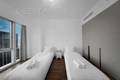two beds in a white room with a window at Grande Tower by Emaar, Downtown, Burj Khalifa in Dubai