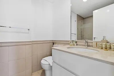 a bathroom with a sink and a toilet and a mirror at Town Square Zahra 2B - 2 Bedroom Apartment - Allsopp & Allsopp in Dubai