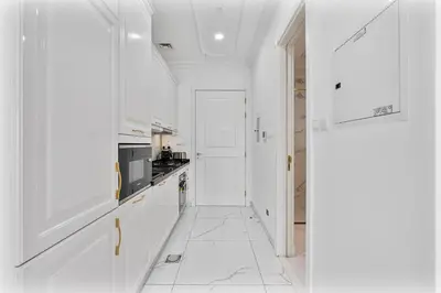a white kitchen with white cabinets and a white floor at Classy Studio APT Close To Dubai Miracle Garden in Dubai