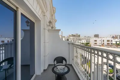 a balcony with two chairs and a view of a city at Classy Studio APT Close To Dubai Miracle Garden in Dubai