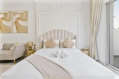 a bedroom with a white bed with two white towels at Classy Studio APT Close To Dubai Miracle Garden in Dubai