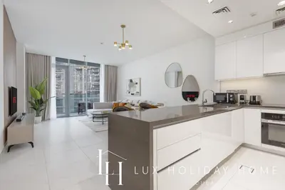 a kitchen with white cabinets and a living room at LUX The Burj Khalifa Lagoon View Suite 4 in Dubai