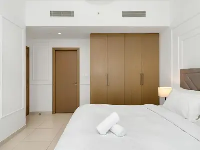 a bedroom with a white bed and wooden cabinets at ABI Holiday Homes - Burj Khalifa and Fountain view Downtown in Dubai