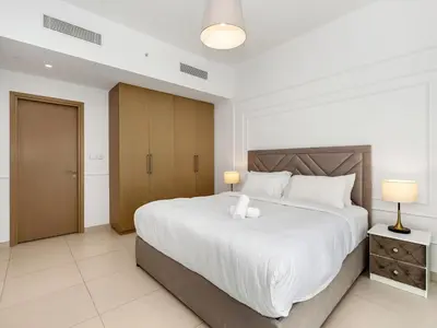a bedroom with a large white bed and two lamps at ABI Holiday Homes - Burj Khalifa and Fountain view Downtown in Dubai