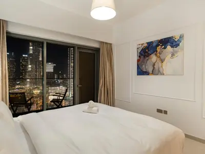 a bedroom with a white bed and a large window at ABI Holiday Homes - Burj Khalifa and Fountain view Downtown in Dubai
