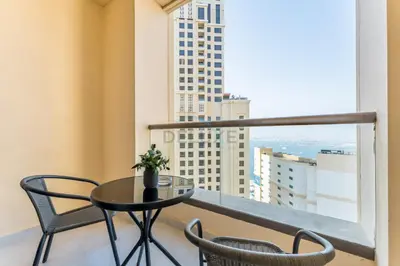 a table and chairs on a balcony with a view at Panoramic Sea and Canal Views from High-Floor 2BR, Steps from Tram and Marina Beach, Shams 2, JBR by Dekuxe Holiday Homes in Dubai