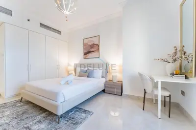 a white bedroom with a bed and a desk at Panoramic Sea and Canal Views from High-Floor 2BR, Steps from Tram and Marina Beach, Shams 2, JBR by Dekuxe Holiday Homes in Dubai