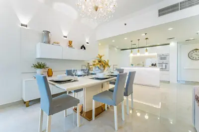a white kitchen with a dining table and chairs at Panoramic Sea and Canal Views from High-Floor 2BR, Steps from Tram and Marina Beach, Shams 2, JBR by Dekuxe Holiday Homes in Dubai
