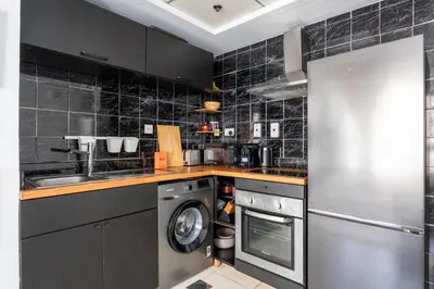 a kitchen with a stainless steel refrigerator and a washer at GuestReady - Cozy Studio | Pool & Gym | Canal view in Dubai