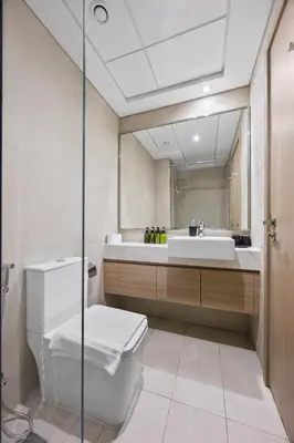 a bathroom with a toilet and a sink and a mirror at Elite Escape - Getaway in Azizi Riviera 29 in Dubai