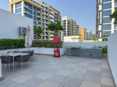 a patio with tables and chairs and an umbrella at Elite Escape - Getaway in Azizi Riviera 29 in Dubai