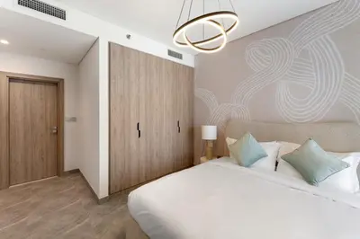a bedroom with a large white bed and a chandelier at Brand New 2BR Peninsula One with Burj Khalifa View in Dubai