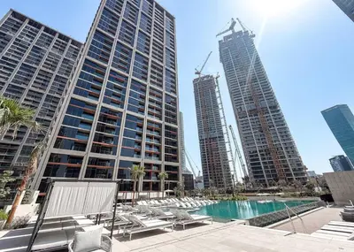 a group of tall buildings in a city with a pool at Brand New 2BR Peninsula One with Burj Khalifa View in Dubai