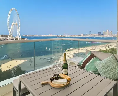a table with a bottle of wine and wine glasses on a balcony at 1st Row Beach Views with Private Beach and Resort Vibes in Dubai
