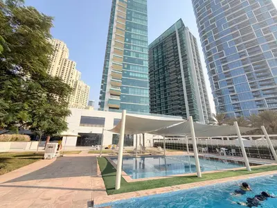 a swimming pool with a white canopy in front of tall buildings at Beachfront Luxury Penthouse at The Walk JBR next to Bluewaters Island - 2BR & Maids Room in Dubai