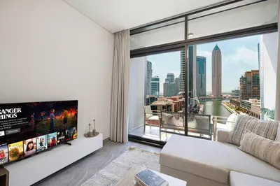 a living room with a tv and a large window at StayMada - Peninsula Panoramic Waterfront Views in Dubai