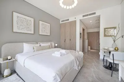 a bedroom with a large white bed and a desk at StayMada - Peninsula Waterfront and Pool Views in Dubai
