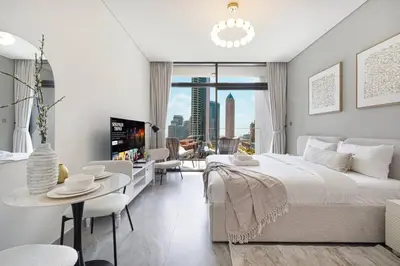 a white bedroom with a large bed and a table at StayMada - Peninsula Waterfront and Pool Views in Dubai