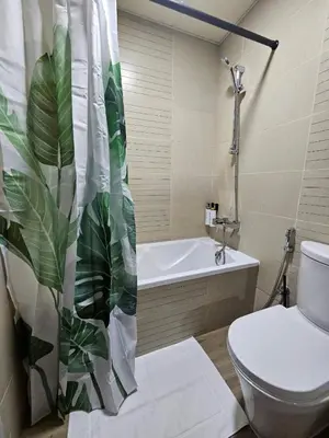 a bathroom with a toilet and a shower curtain with a plant at JLT Studio, Steps to Metro, High floor, Smart Home in Dubai