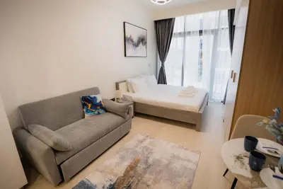 a living room with a couch and a bed at Azizi Modern Studio 10 min to Downtown in Dubai
