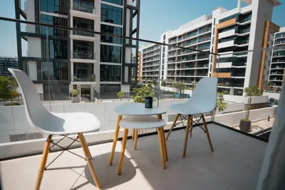 three chairs and a table on a balcony with buildings at Azizi Modern Studio 10 min to Downtown in Dubai