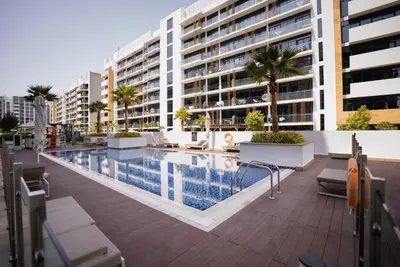 a swimming pool in front of a building at Azizi Modern Studio 10 min to Downtown in Dubai
