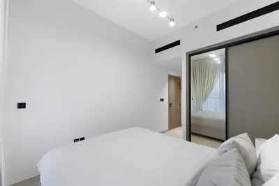 a white bedroom with a bed and a mirror at Elegant 1BR Stay in Binghatti Heights JVC in Dubai