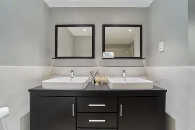 a bathroom with two sinks and two mirrors at FAM Living - 1 Bedroom in Rimal 2 Dubai Marina in Dubai