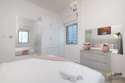 a white bedroom with a large bed and a sink at Serene Beachside Two-Bedroom Retreat in Dubai