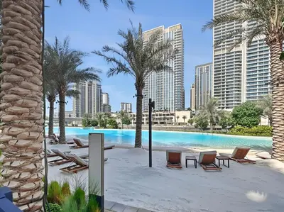 a pool with chairs and palm trees and buildings at Creek Beach Sunset 3! Lagoon Access! in Dubai
