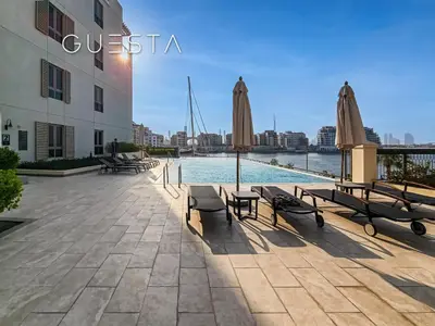a swimming pool with chairs and umbrellas next to a building at La Cote by Merass, La Mer Dubai in Dubai