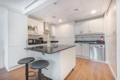 a kitchen with white cabinets and a counter with stools at StayShort - Sophisticated unit in JLT Sleeps 6 with Lake Views in Dubai