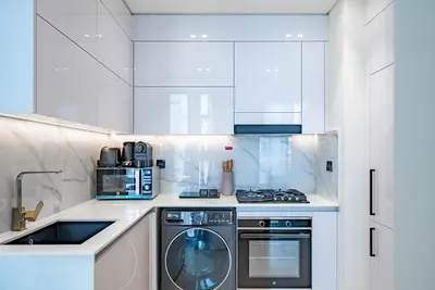 a white kitchen with a washer and dryer in it at Homes Beyond l 1BR Cozy Modern Escape in JVC in Dubai