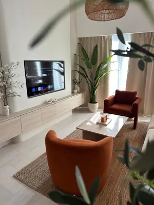 a living room with a television and a couch and chair at Stunning 1-Bedroom Apartment , Full Marina View in Dubai
