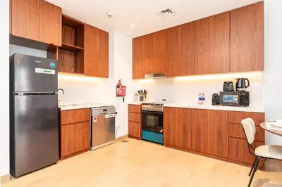 a kitchen with wooden cabinets and a stainless steel refrigerator at PVH - Breezy 1BR with Partial Sea View - La Sirene in Dubai