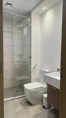 a bathroom with a shower and a toilet and a sink at Modern & Fully Furnished 1BR in Heart of JVC in Dubai