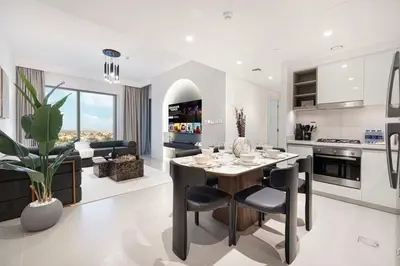 a kitchen with a table and chairs and a living room at Elegant 2BR Downtown Dubai Walk to Dubai Mall in Dubai