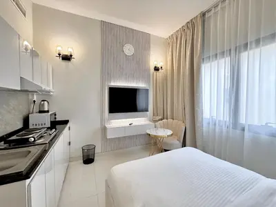 a white hotel room with a bed and a television at Signature Vista Studio Apartment in Dubai