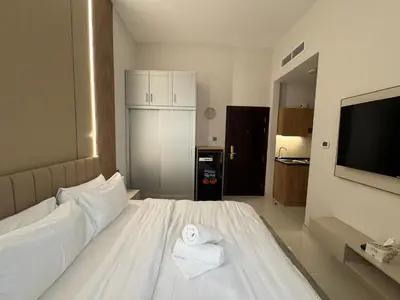 a bedroom with a white bed and a television at Signature Grand Studio Apartment in Dubai