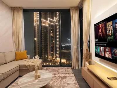 a living room with a couch and a large window at Royal Vista - Stunning Boho Style 1BR with 5 Star Amenities in Dubai
