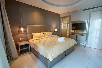 a bedroom with a large bed and a television at DAMAC Paramount Towers 2BHK by WS Holiday Homes in Dubai