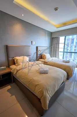 two beds in a hotel room with a large window at DAMAC Paramount Towers 2BHK by WS Holiday Homes in Dubai
